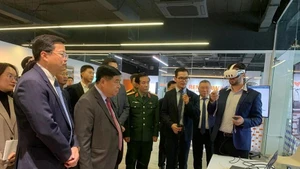 Le vice-Premier ministre Nguyen Chi Dung et les délégués écoutent la présentation du Centre de recherche-développement (R&D) et du Centre d’Excellence consacrés à l’intelligence artificielle et au jumeau numérique. Photo : Quan doi nhan dan