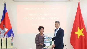 L'ambassadeur Nguyen Minh Vu remet des cadeaux du Têt à Ha Thi E, qui a contribué à la résistance contre l'armée américaine et a reçu un certificat de mérite du Premier ministre vietnamien en 2009. Photo : VNA.