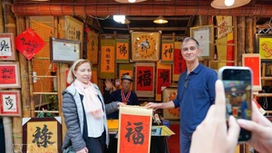 Des visiteurs internationaux participent à l’activité traditionnelle de demande de calligraphie en début d’année. Photo : VNA.