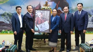 Nguyen Dinh Vinh, secrétaire adjoint permanent du Comité municipal du Parti de Da Nang, et Phan Thai Son, représentant par intérim du journal Nhan Dan pour la région Centre-Hauts Plateaux du Centre, ont offert aux dirigeants de la province d’Attapeu une photo du Président Ho Chi Minh lisant le journal Nhan Dan. Photo : Anh Dao.
