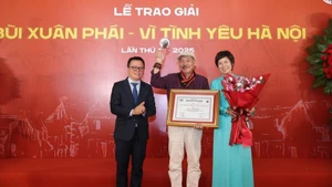Lê Quôc Minh (à gauche), membre du Comité central du Parti, chef adjoint de la Commission de la sensibilisation, de l'éducation et de la mobilisation de masse du Comité central du Parti et président de l'Association des journalistes vietnamiens, et Vu Viêt Trang (à droite), directrice générale de l'Agence vietnamienne d’information, remettent le Grand prix au musicien Trân Tiên. Photo : NDEL