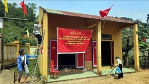 Des habitants de l’ethnie Bru-Van Kieu du village de Nuoc Dang décorent le bureau de vote afin de se préparer au scrutin anticipé prévu le 8 mars. Photo : VNA.