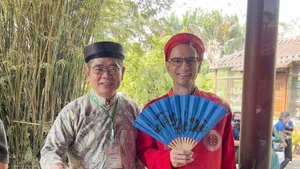 Des diplomates étrangers vêtus de l’ao dai traditionnel vietnamien lors de l'événement. Photo : VNA.