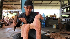 Un menuisier sculpte avec minutie chaque détail d’un mascotte en forme de cheval pour le marché du Têt. Photo : Vietnamnet.