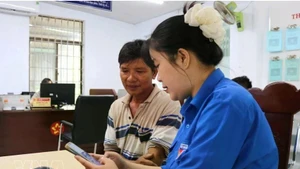 Une membre de l'anntenne de l'Union de la jeunesse communiste Ho Chi Minh à Dak Lak, aide un haibitant local à effectuer une démarche administrative en ligne. Photo : VNA.