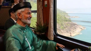 Un touriste étranger, vêtu d’áo dài, a admiré le paysage du col de Hai Van et de la baie de Lang Co à travers la fenêtre. Photo : Znews.