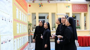 Des religieuses de la Congrégation des Amantes de la Sainte-Croix, au 31 rue Nhà Chung, consultent la liste des candidats au bureau de vote n°1, dans le quartier de Hoàn Kiem. Photo : VNA