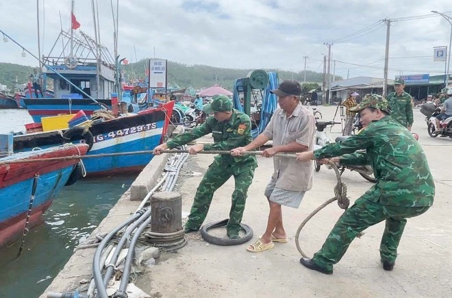 Des garde-frontières de Quang Ngai aident des pêcheurs à ancrer leurs bateaux. Photo: VNA