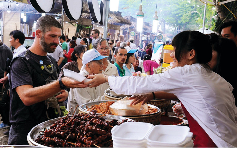 Un touriste étranger (gauche) découvre la cuisine de rue à Hanoï. Un touriste étranger (gauche) découvre la cuisine de rue à Hanoï.