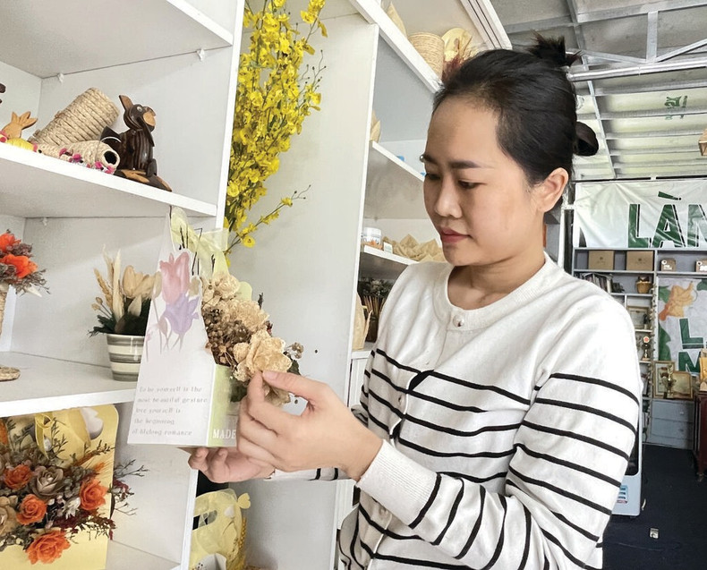 Une cliente choisit des produits dans l’espace d’exposition du Làng muop.