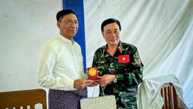 Le général de brigade Pham Van Ty (à droite), vice-directeur du Département des Secours et du Sauvetage relevant de l’État-major général, et chef de la délégation de l'Armée populaire vietnamienne, présente un cadeau au représentant du ministère de la Solidarité sociale, de la Gestion des catastrophes et de la Reconstruction du Myanmar. Photo : nhandan.vn