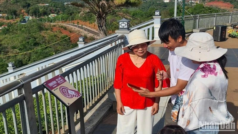 Guide des visiteurs pour effectuer les opérations de check-in sur les panneaux équipés de puces NFC installés dans la ville de Gia Nghia, province de Dak Nông. Photo: nhandan.vn