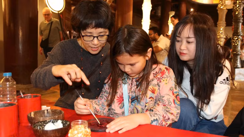 Des artistes et des visiteurs réalisent ensemble des œuvres en laque traditionnelle au Temple de la Littérature – Quoc Tu Giam. Photo : nhandan.vn Des artistes et des visiteurs réalisent ensemble des œuvres en laque traditionnelle au Temple de la Littérature – Quoc Tu Giam. Photo : nhandan.vn
