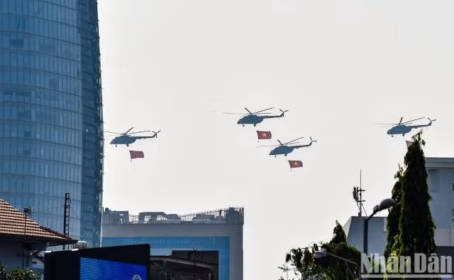 Les hélicoptères Mi-8 et Mi-17, arborant le drapeau du Parti et le drapeau national, se dirigent vers l’estrade officielle. Photo : nhandan.vn