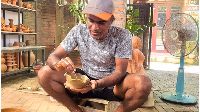 Un visiteur étranger fait l'expérience de façonner des produits céramiques. Photo : kinhtedothi.vn Un visiteur étranger fait l'expérience de façonner des produits céramiques. Photo : kinhtedothi.vn