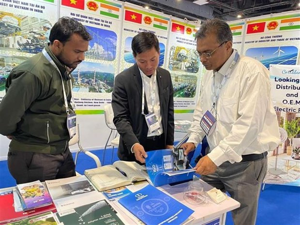 Un cadre de l’Office du commerce du Vietnam en Inde (au milieu) présente des informations aux visiteurs. Photo : VNA.