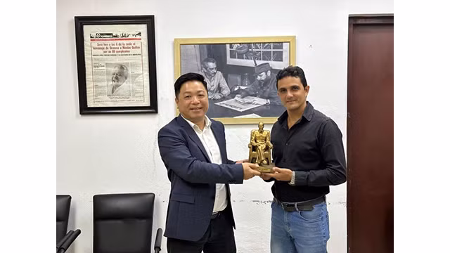 Le camarade Quê Dinh Nguyên (à gauche), rédacteur en chef adjoint du Journal « Nhân Dân » (Le Peuple) présente un cadeau de souvenir au rédacteur en chef du Journal Granma. Photo : NDEL.