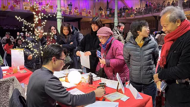  La table de calligraphie attire de nombreux gens. Photo : VNA.