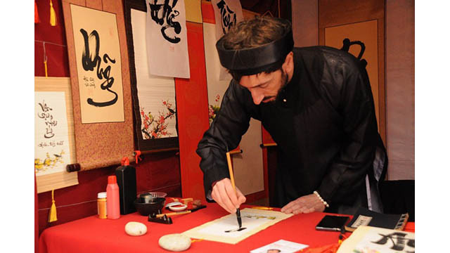 Jean Sébastien Grill, un étranger « Ông dô » (maître calligraphe) porte un « áo the » (tunique traditionnelle masculine vietnamienne) et un « khăn xếp » (turban), ses yeux se sont concentrés sur chaque coup de plume. Photo : thoidai.com.vn