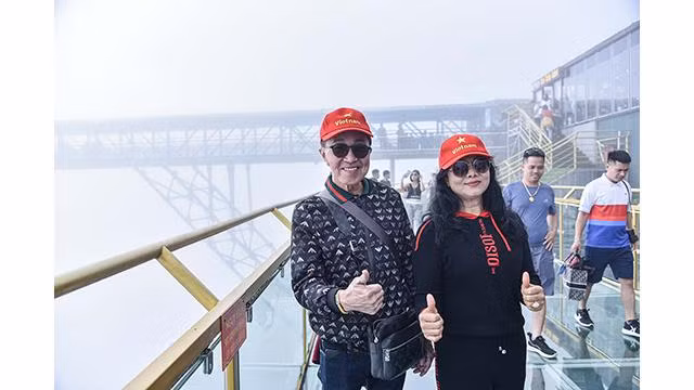 Les touristes étrangers prennent des photos lors de la visite au pont en verre Rông Mây. Photo: baoquocte.vn