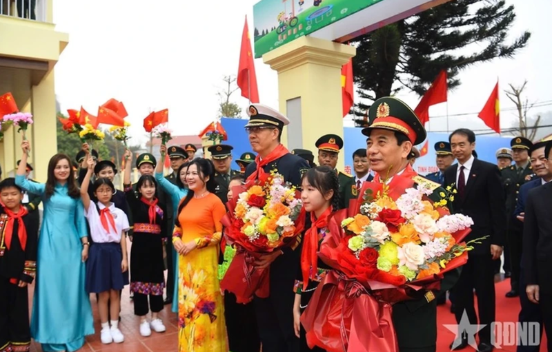 Des élèves offrent des fleurs aux deux ministres de la Défense, Phan Van Giang et Dong Jun Photo : qdnd.vn