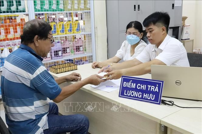 Une personne âgée d'Hô Chi Minh-Ville reçoit une pension dans un bureau de poste. Photo : VNA.