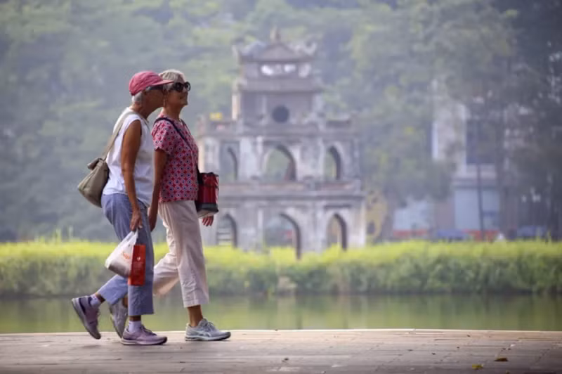 Des touristes étrangers se promenant au bord du lac Hoàn Kiêm. Photo : VNA/CVN.