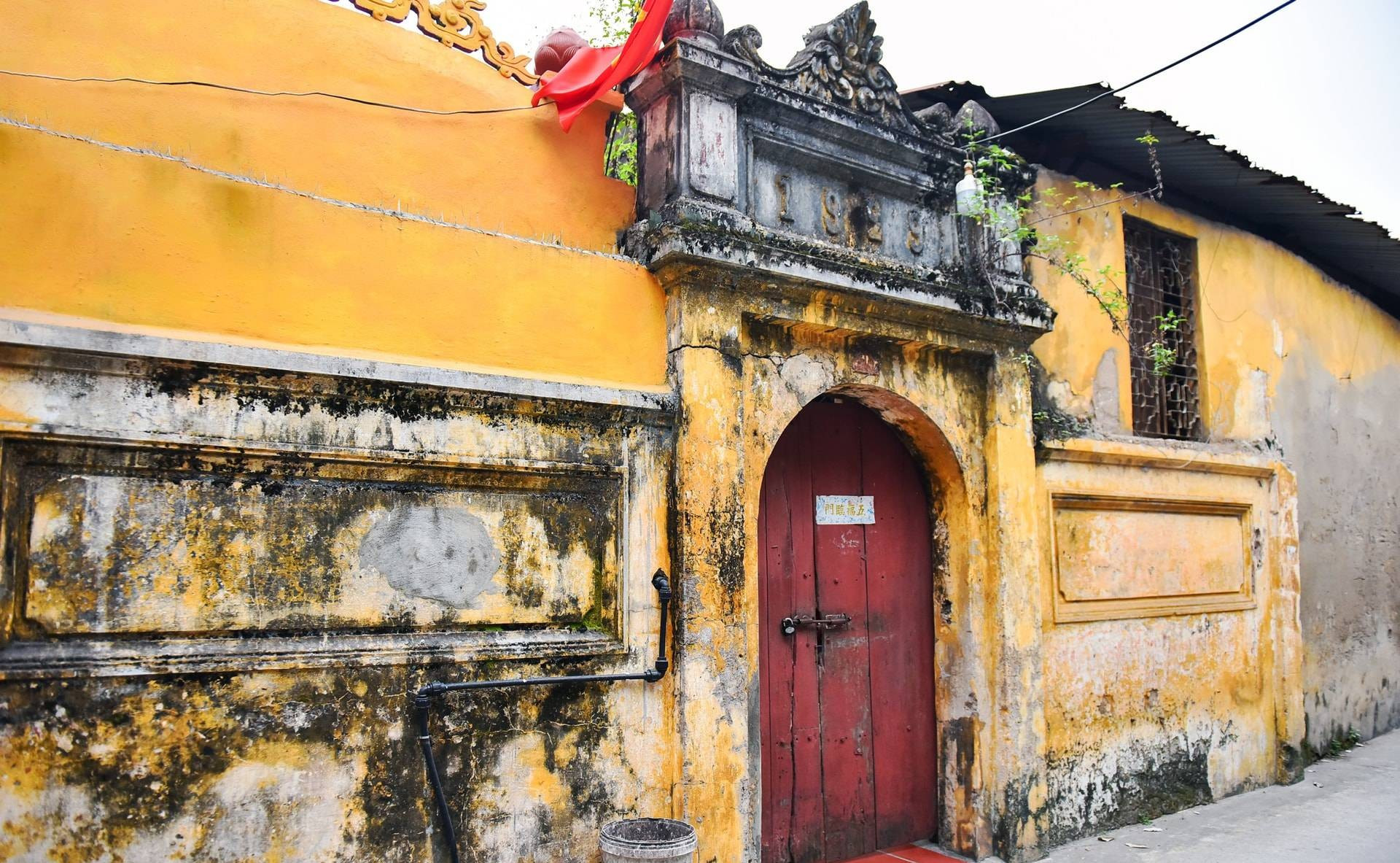 Le portail d’une maison datée de 1929, couvert de mousse et marqué par les fissures du temps, nécessite des mesures de relevé, de consolidation et une protection efficace contre l’humidité. Photo : hanoimoi.vn