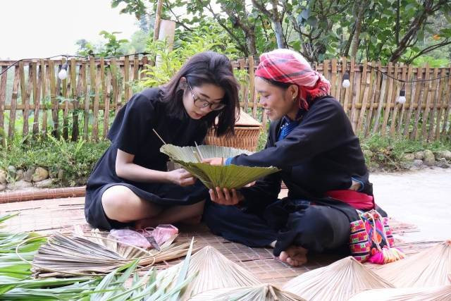 Lam Thị Nghi guide les visiteurs dans l’expérience de fabrication du chapeau en feuilles de palmier. Photo: vietnamnet.vn anh-3-2218.jpg