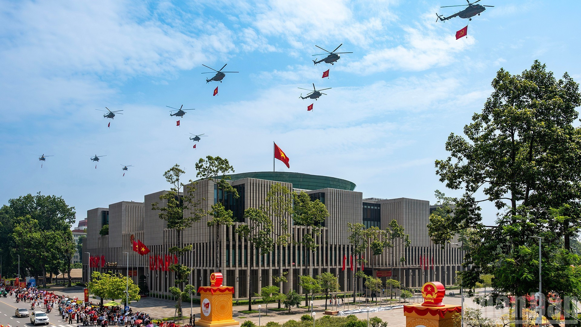 Une formation de dix hélicoptères arborant le drapeau du Parti et le drapeau national survolent la place Ba Dinh. Photo : Giang Huy.