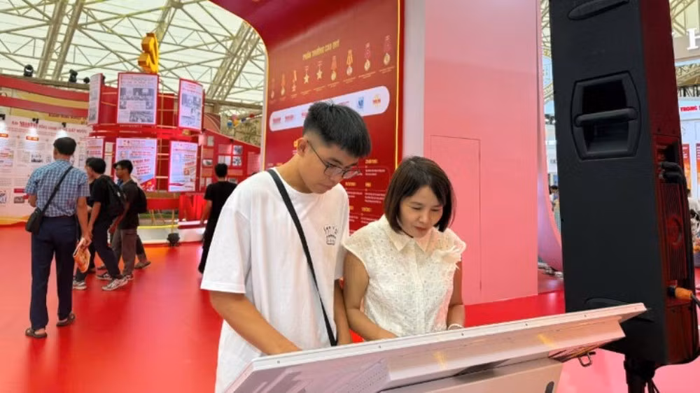 Les visiteurs découvrent le modèle numérique interactif « 95 ans - le drapeau du Parti éclaire la voie » du Journal Nhân Dân. Photo : NDEL.
