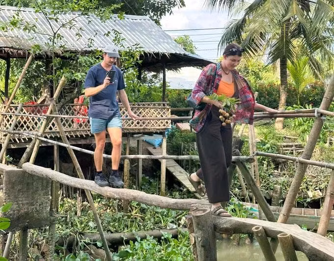 Des visiteurs découvrent l’expérience de la traversée d’un petit « pont suspendu », passerelle traditionnelle typique du delta du Mékong. Photo : SGGP.