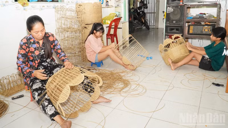 Mme Mai Thi Kim Phung et les membres de sa famille finalisent leurs produits artisanaux. 