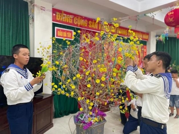 Un groupe de soldats attachent des fleurs d'abricot en tissu aux troncs d'arbres. Photo : NDEL Un groupe de soldats attachent des fleurs d'abricot en tissu aux troncs d'arbres. Photo : NDEL