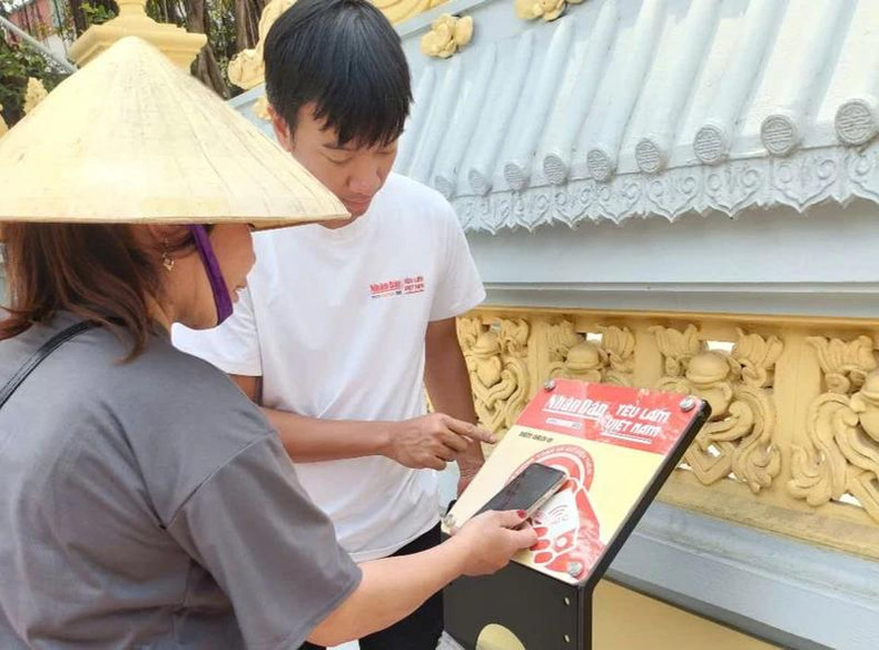 Une voyageuse effectue les opérations de check-in sur le panneau équipé de puces NFC installé au temple de Lanh Giang. Photo : NDEL. Une voyageuse effectue les opérations de check-in sur le panneau équipé de puces NFC installé au temple de Lanh Giang. Photo : NDEL.