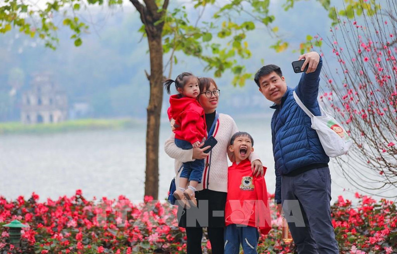Une famille pose au bord du lac Ho Guom (Épée restituée) à Hanoi. Photo : VNA. Une famille pose au bord du lac Ho Guom (Épée restituée) à Hanoi. Photo : VNA.