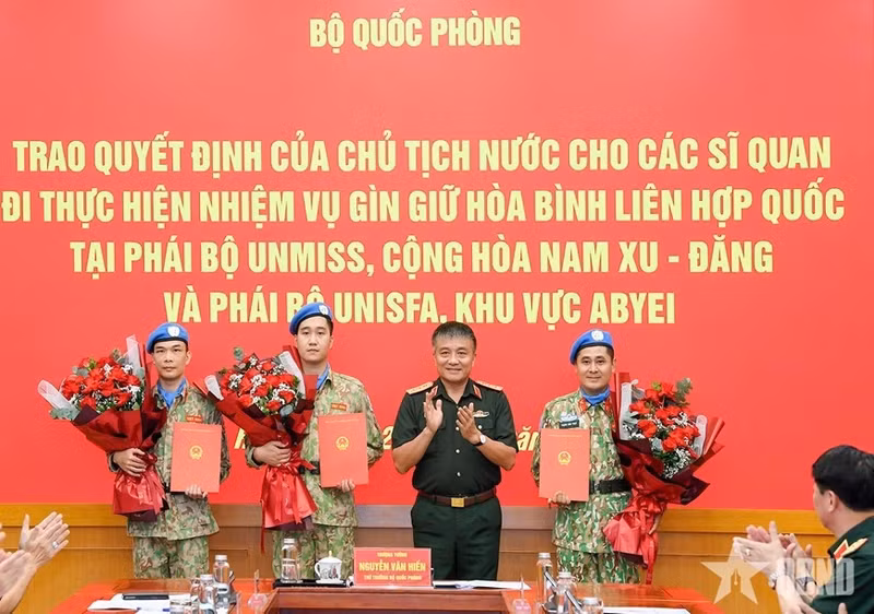 Le général de corps d’armée Nguyen Van Hien remet la décision du président à trois officiers chargés de participer à des missions de maintien de la paix des Nations Unies. Photo : QDND.