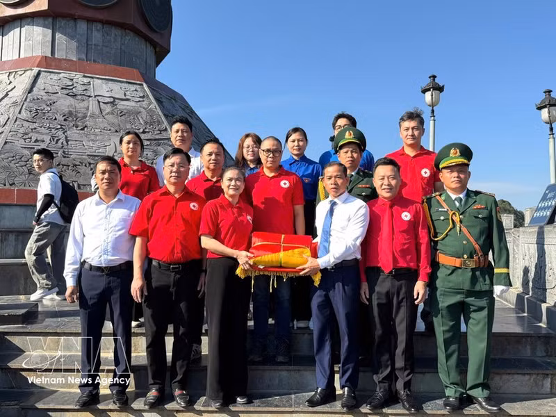Duong Ngoc Duc, secrétaire du Comité du Parti et président du Conseil populaire de la commune de Lung Cu, remet à Do Thi Thu Thao le drapeau national. Photo : VNA.