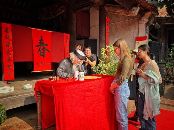 Un vieux calligraphe en plein travail, sous le regard admiratif des visites étranger. Photo : VNA. Un vieux calligraphe en plein travail, sous le regard admiratif des visites étranger. Photo : VNA.