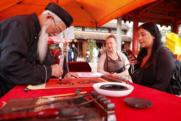 Des visiteurs étrangers demandent des calligraphies. Photo : VNA Des visiteurs étrangers demandent des calligraphies. Photo : VNA