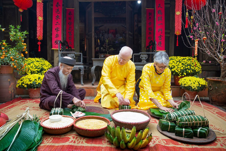Des touristes étrangers découvrent la préparation du bánh chưng dans l'ancien village de Duong Lâm. Photo : Nina May. Des touristes étrangers découvrent la préparation du bánh chưng dans l'ancien village de Duong Lâm. Photo : Nina May.