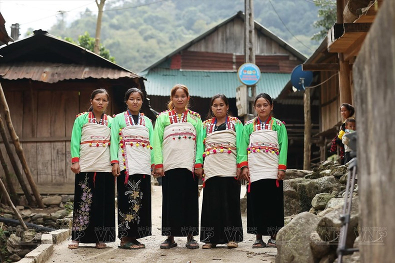 La particularité des costumes des femmes Mảng est la cape en tissu brut blanc, brodée de fil rouge et enroulée autour du corps. La particularité des costumes des femmes Mảng est la cape en tissu brut blanc, brodée de fil rouge et enroulée autour du corps.