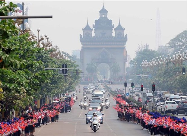 Hommes, femmes et enfants agitent les drapeaux du Vietnam et du Laos au passage du convoi du Président Vo Van Thuong, à Vientiane, le 10 avril. Photo : VNA.