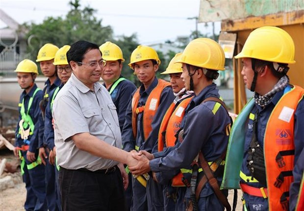 Le Premier ministre Pham Minh Chinh et des ouvriers qui construisent le pont Nguyên Hoàng sur la rivière Huong. Photo : VNA. Le Premier ministre Pham Minh Chinh et des ouvriers qui construisent le pont Nguyên Hoàng sur la rivière Huong. Photo : VNA.