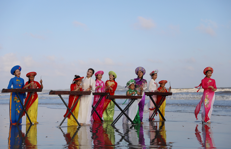 Les femmes Kinh de Sandao portent l’"áo dai", jouent du "đàn bầu" (monocorde) et chantent des chansons vietnamiennes. Photo de : Baidu. Les femmes Kinh de Sandao portent l’"áo dai", jouent du "đàn bầu" (monocorde) et chantent des chansons vietnamiennes. Photo de : Baidu.