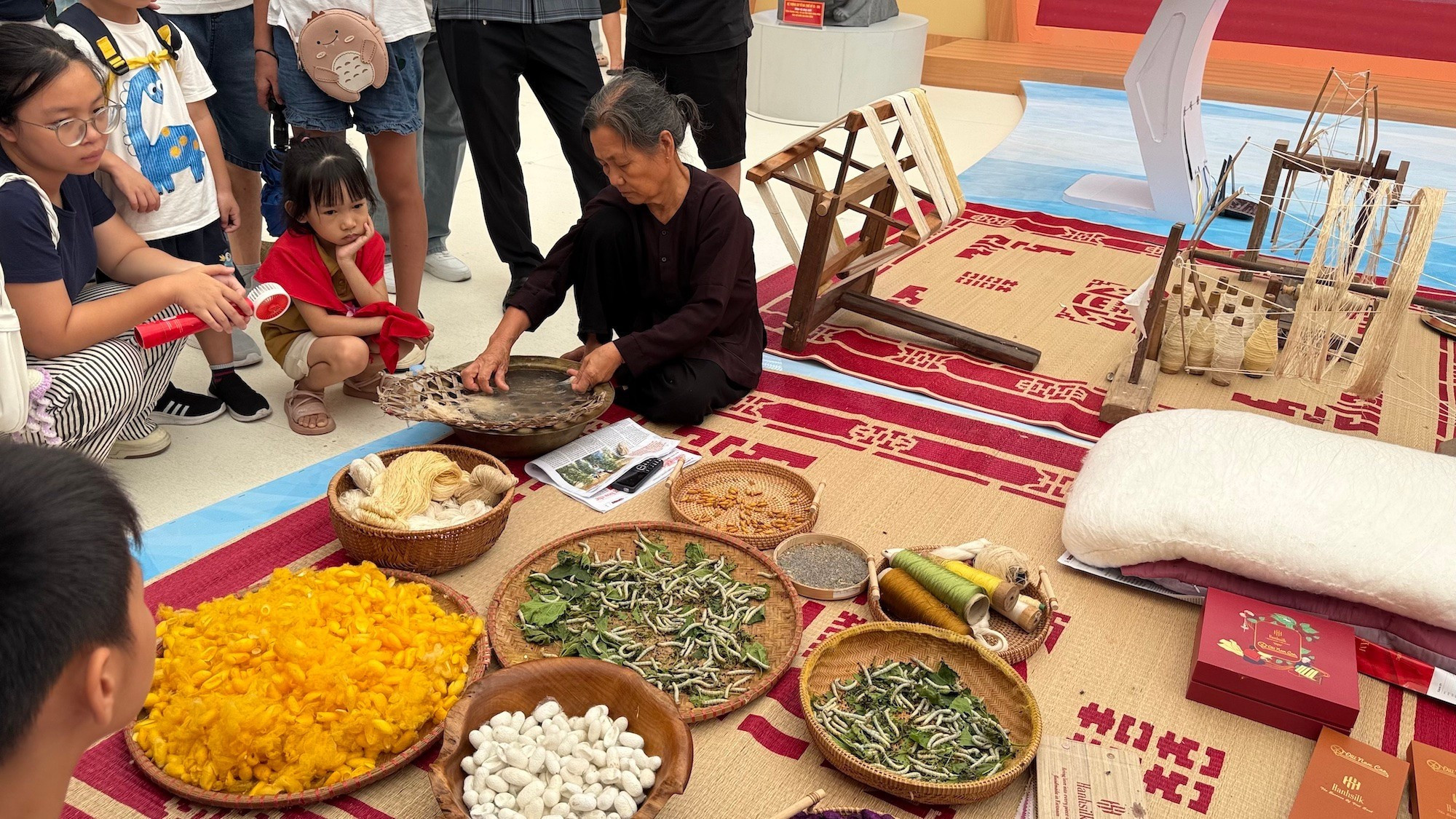 Les visiteurs observent avec attention un artisan extrayant la soie au stand d’exposition de la province de Hung Yen. Les visiteurs observent avec attention un artisan extrayant la soie au stand d’exposition de la province de Hung Yen.