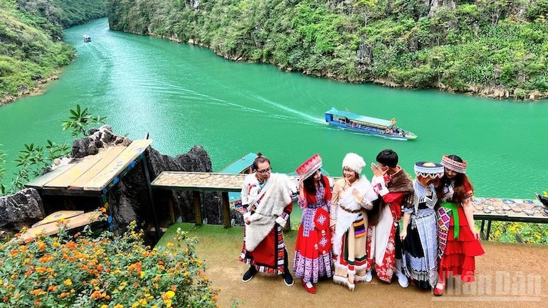 Un groupe de jeunes apprécie l’expérience de porter des costumes traditionnels pour se promener le long de Nho Que.