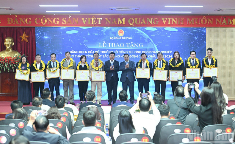 Le Premier ministre Pham Minh Chinh et le ministre de l’Industrie et du Commerce Nguyen Hong Dien remettent des fleurs et des récompenses aux entreprises ayant réalisé des performances d’excellence.