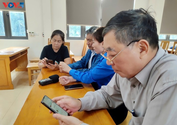 Les membres de l'Union de la jeunesse communiste Hô Chi Minh de la commune de Hai Lang guide les cadres villageois sur l'utilisation de l'application VNeID. Photo: Vu Miên/VOV-Nord-Est