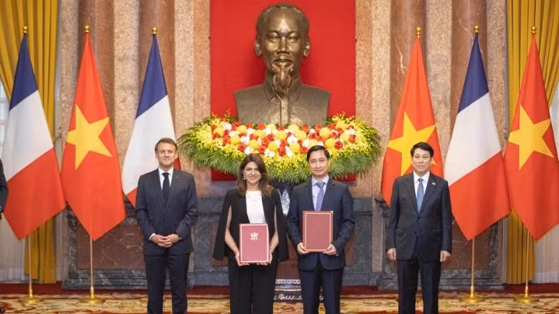 M. Ngo Chi Dung, directeur général et président du conseil d’administration de la société Vietnam Vaccine (VNVC), et Mme Zainab Sadat Qayyum, présidente de Sanofi Asie du Sud-Est – Inde, échangent les documents de l’accord de coopération sur le transfert de technologie de production de vaccins de Sanofi à l’usine de vaccins et produits biologiques de VNVC, en présence du président vietnamien Luong Cuong et du président français Emmanuel Macron. Photo : Son Tung
